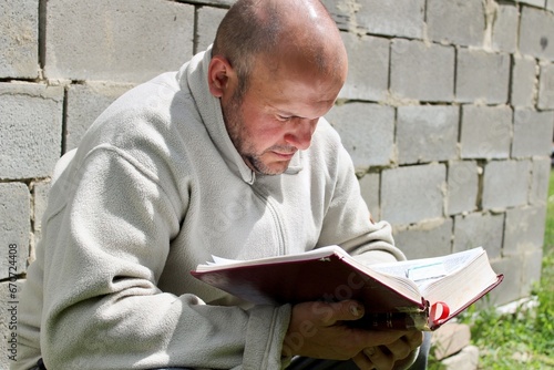 A man sits in the yard and reads a book