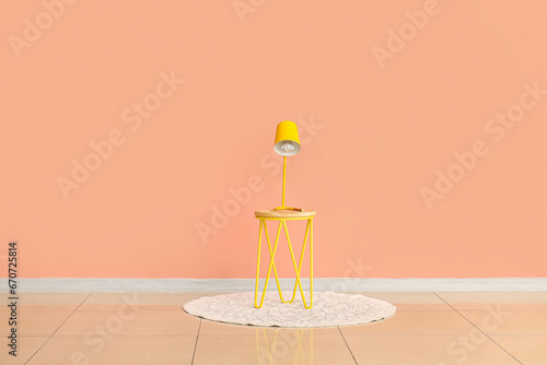 Yellow desk lamp on small table near pink wall