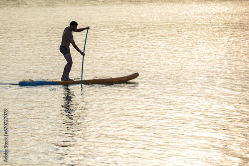 Man standing on the supboard on the middle of the lake. photo