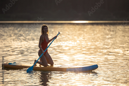 Young woman supsurfing at sunrise. photo