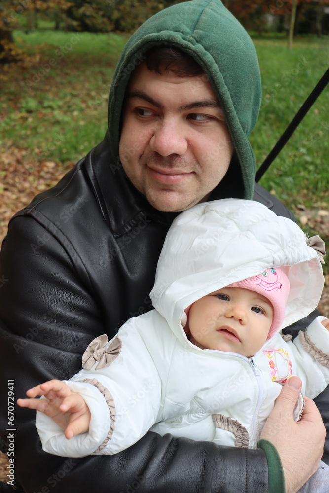 dad holds a little girl in his arms and rides on a swing in the park in autumn dad holds a little girl in his arms and rides on a swing in the park in autumn