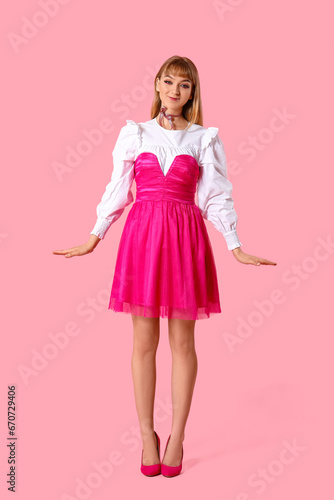 Young woman dressed as doll on pink background