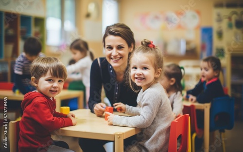 Group of school toddlers playing inside a kindergarten classroom with a woman teacher