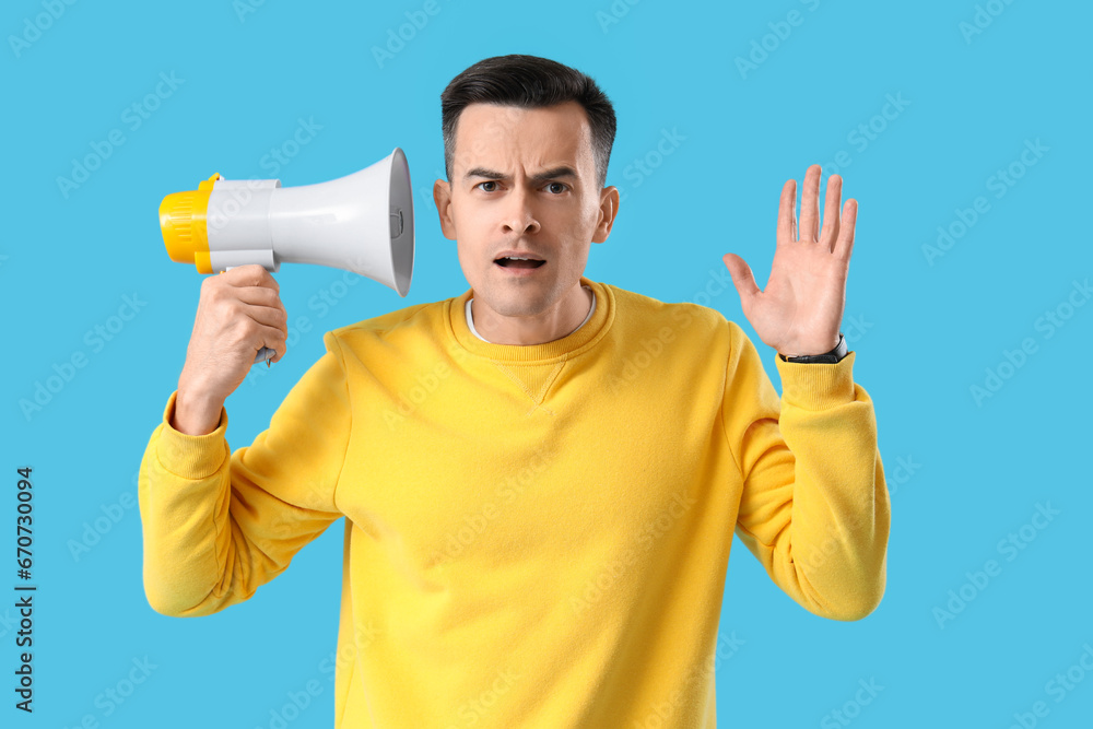 Young man with hearing problem and megaphone on blue background Young man with hearing problem and megaphone on blue background
