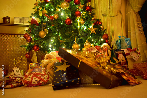 Close-up of colorful Presents and gift boxes under a Christmas tree with bright light in the cozy living room, decoration on Christmas holiday in the UK.