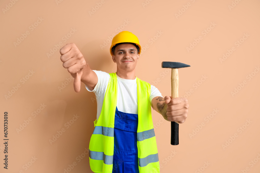 Male worker with hammer showing dislike on beige background