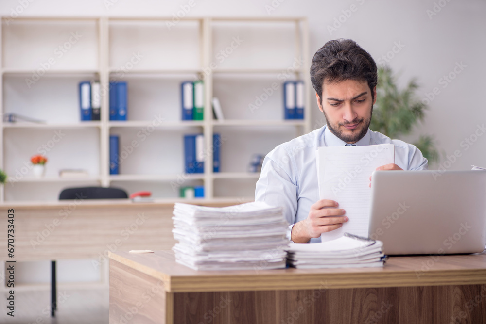 Young male employee and too much work in the office