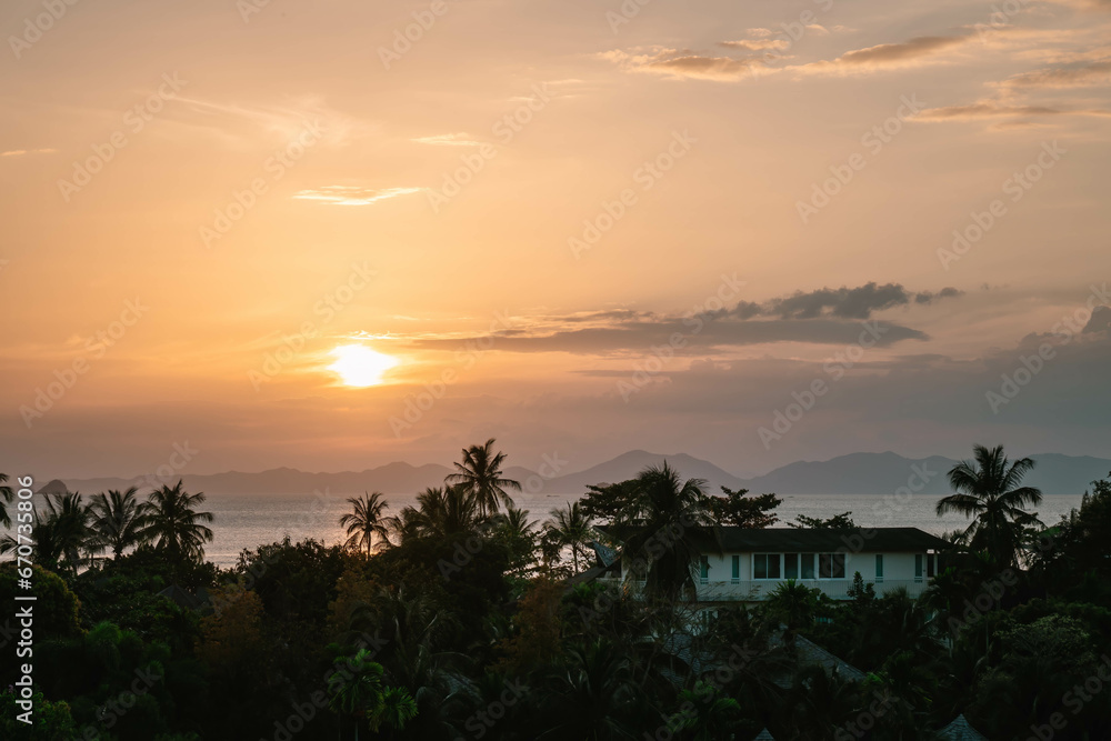 Bright golden evening Sun - close up view on palms, sea and mountains at horizon line. Ao Nang, Thailand