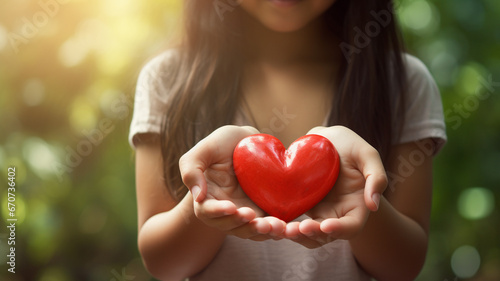 close up of woman 's hands holding red heart with blurred bokeh background. love and health care concept