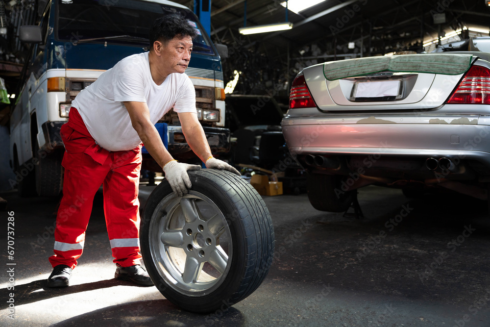mechanic holding and pushing a tire for fixing in garage mechanic holding and pushing a tire for fixing in garage