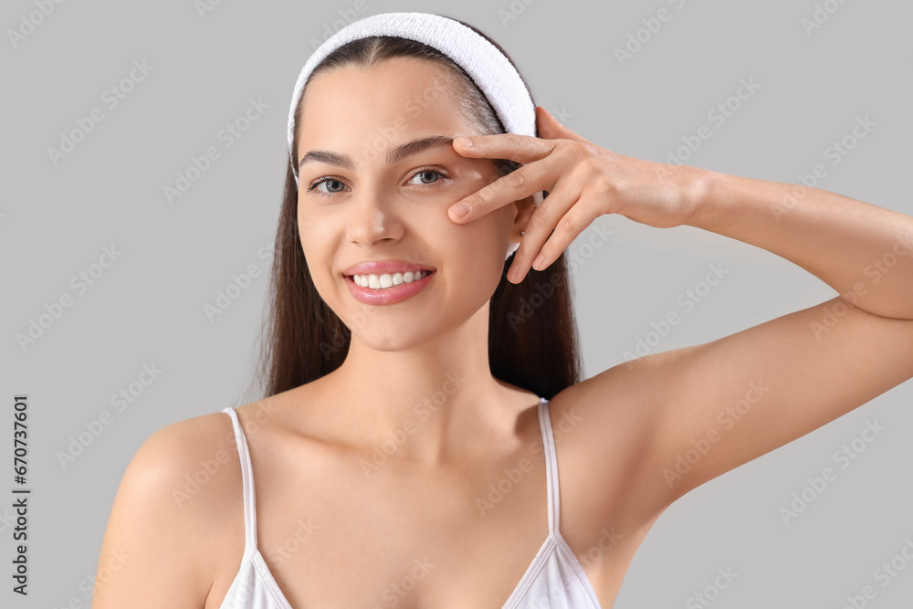Beautiful young woman massaging her face on light background, closeup Beautiful young woman massaging her face on light background, closeup