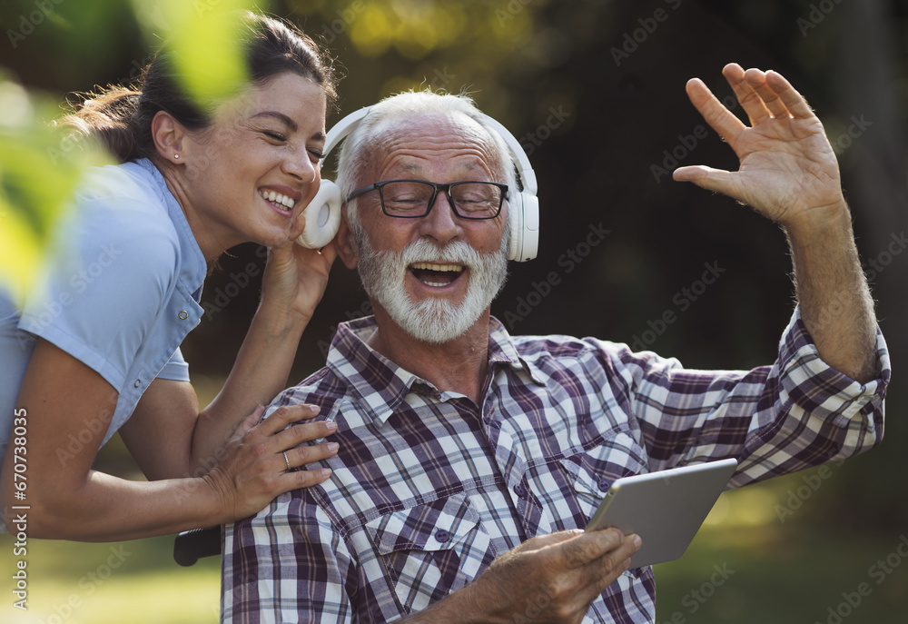 Fototapeta premium Senior man with nurse listening music in park