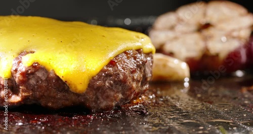 Macro shot of frying beef halal cutlets with melted cheese on top. Cinematic advertisement burger cooking. Perfect beef cutlet fried in a pan with rosemary sprigs and garlic. Traditional meal.