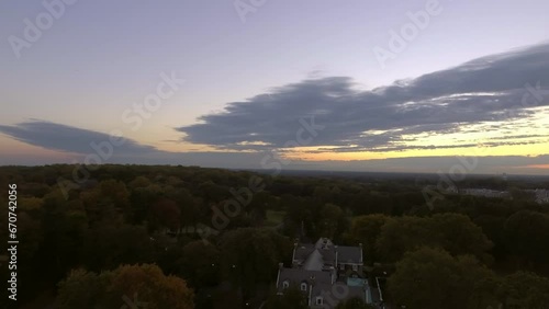 Aerial Panning Shot Of Golf Course Near Buildings And Vehicles Against Sky At Sunset - Manhasset, New York photo