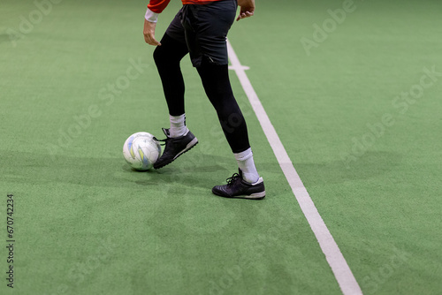 Player preparing to hit the ball on mini soccer match in sports hall.
