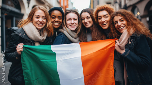 cheerful friends holding the flag of Ireland on the street of Dublin, young smiling Irish women, symbol of the country, St. Patrick's Day, international, joyful girls in the city, national, green