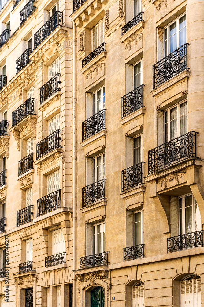 Façade of a typical and elegant residential building in Passy quarter, in Paris, France, with wrought iron railings and balconies 