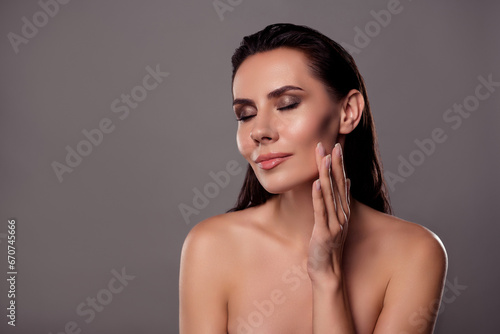 Photo portrait of lovely young lady closed eyes cheek apply cream spa salon isolated on dark gray color background