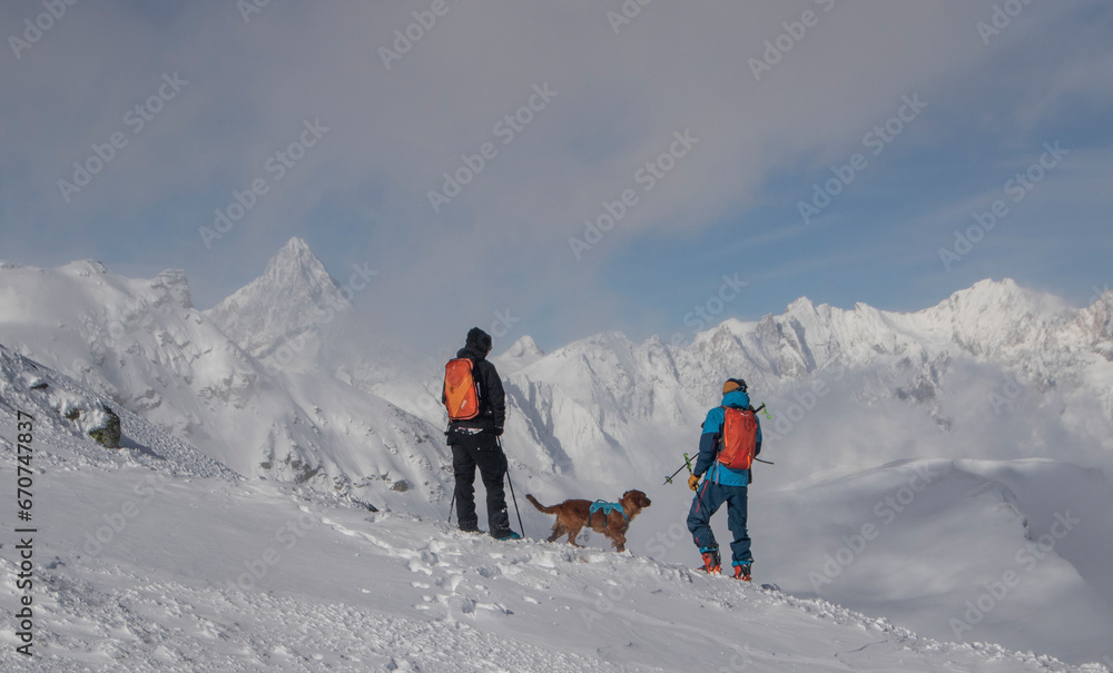 Persons hiking with pet dog on snow mountain during vacation Persons hiking with pet dog on snow mountain during vacation