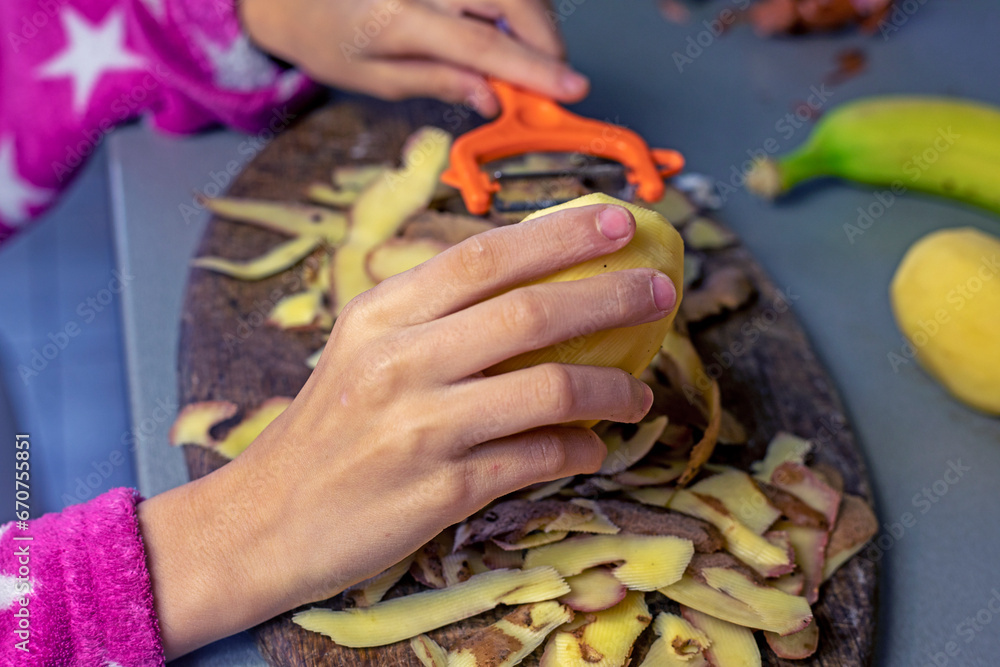 girl's hands peeling potato skins in the kitchen before cooking