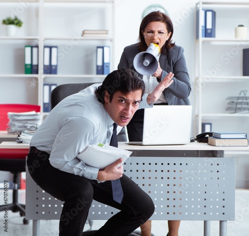 Foto Old female boss and young male employee in the office