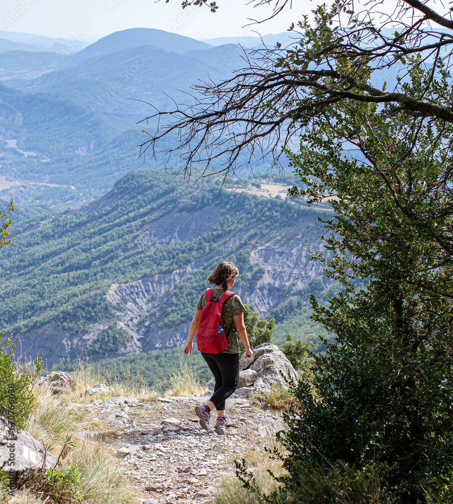 Caucasian girl young woman in sports clothes going down the stone path between the mountains with a backpack on her back
