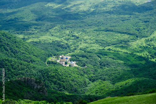 View of the green slopes of the mountains and the chirch below in a valley photo