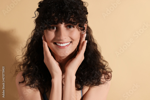 Portrait of beautiful young woman on beige background