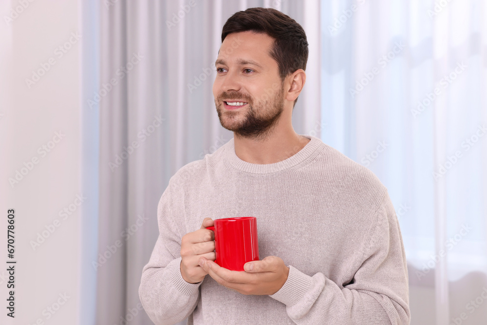 Happy man holding red ceramic mug at home Happy man holding red ceramic mug at home
