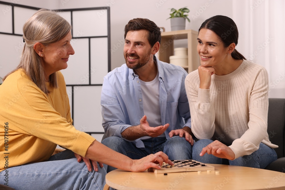Fototapeta premium Family talking while playing checkers at home