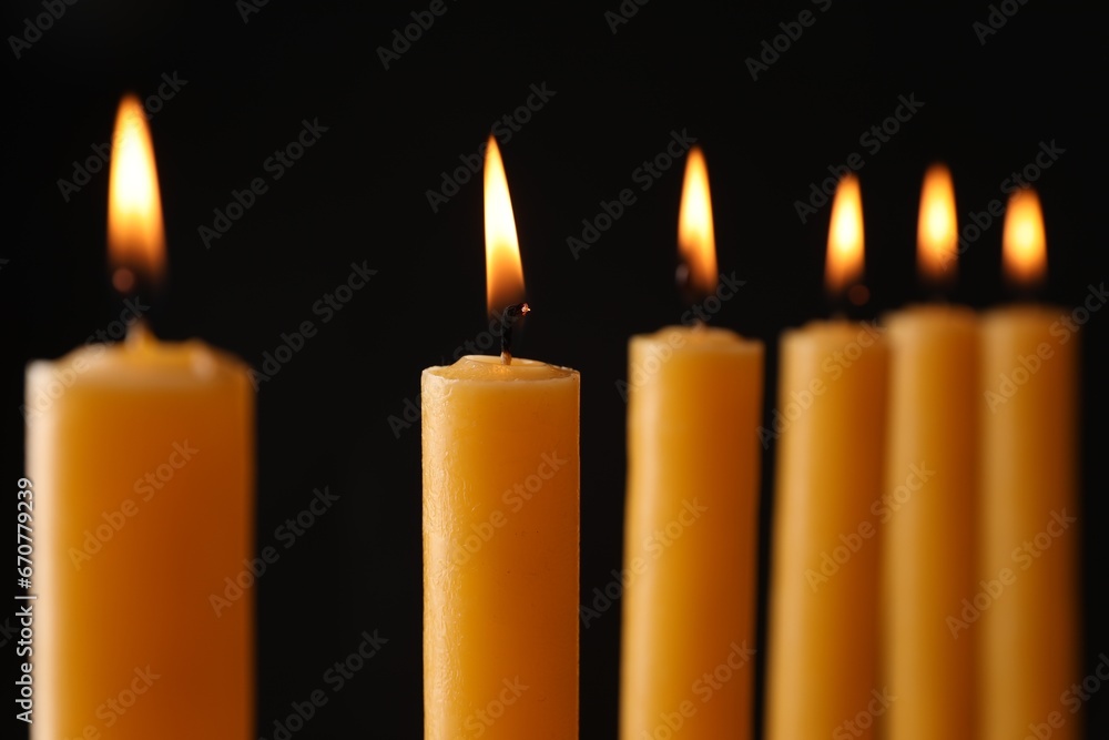 Many burning church candles on black background, closeup Many burning church candles on black background, closeup