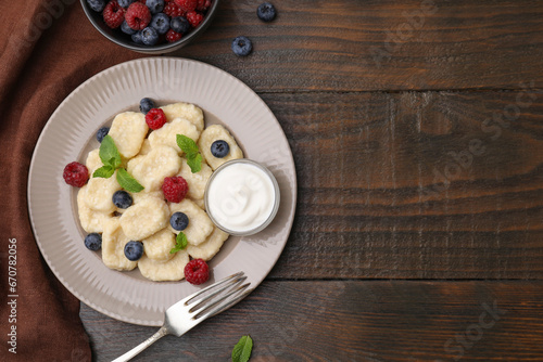 Plate of tasty lazy dumplings with berries, sour cream and mint leaves on wooden table, flat lay. Space for text