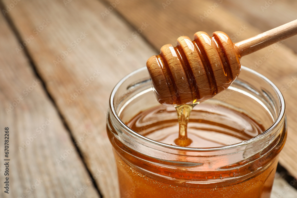 Pouring honey from dipper into jar on table, closeup. Space for text Pouring honey from dipper into jar on table, closeup. Space for text