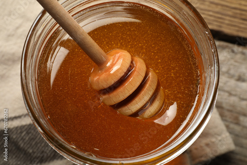 Dipper with honey in jar on table, top view