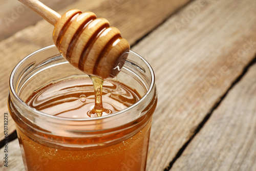 Pouring honey from dipper into jar on table, closeup. Space for text