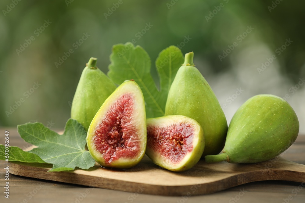 Cut and whole green figs on table against blurred background, closeup