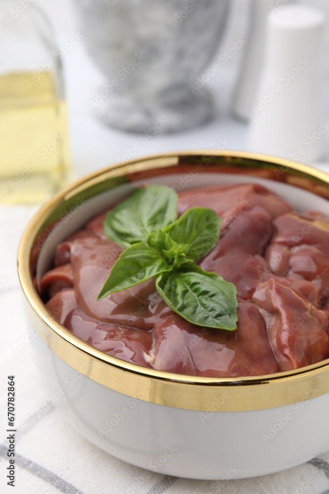 Bowl with raw chicken liver and basil on table, closeup Bowl with raw chicken liver and basil on table, closeup