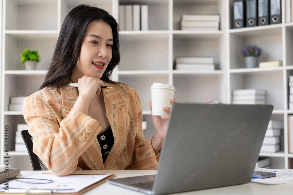 Cheerful businesswoman working with laptop, female office worker smiling charmingly. Work with financial documents to analyze company financial data. Cheerful businesswoman working with laptop, female office worker smiling charmingly. Work with financial documents to analyze company financial data.