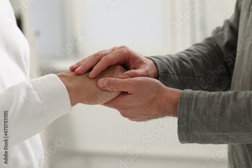 Trust and support. Men joining hands indoors, closeup