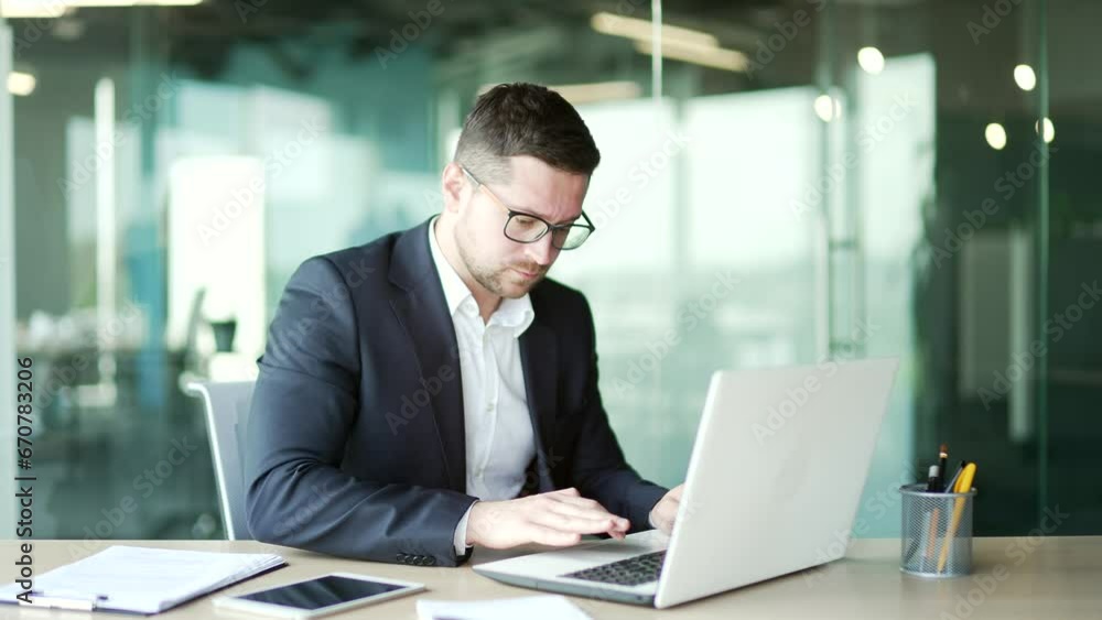 Frustrated businessman in a formal suit having problems with software or service on laptop computer sitting in business office. Worried disappointed worker complains about a bad internet connection Frustrated businessman in a formal suit having problems with software or service on laptop computer sitting in business office. Worried disappointed worker complains about a bad internet connection