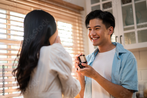 Asian romantic man making surprise proposal of marriage to girlfriend. 