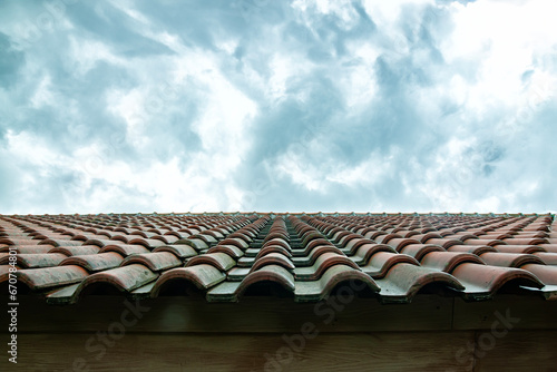 the shape of the roof of the house is made of red tiles with a bright, cloudy sky in the background