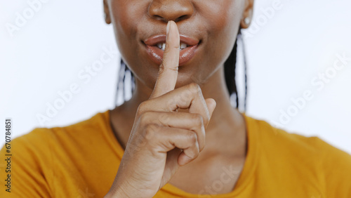 Secret, finger to lips and black woman in studio for privacy, confidential information and face on white background. Mouth zoom, quiet and silence gesture with emoji, gossip or whisper with news photo