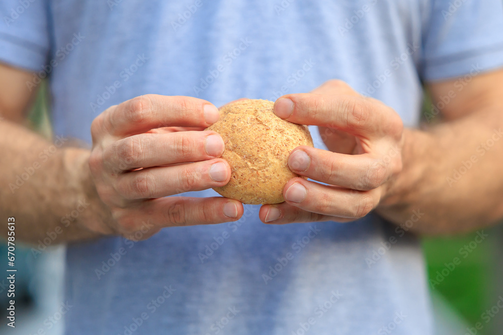 Man's hand holds mini bread, snack and fast food concept. Selective focus on hands with blurred background Man's hand holds mini bread, snack and fast food concept. Selective focus on hands with blurred background