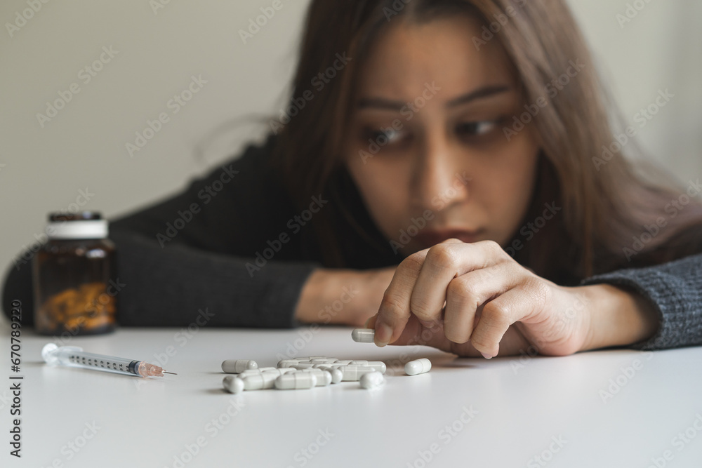 Anti drugs, drug addict asian young woman hand holding pills, medicament with narcotic syringe on table at home, abuse overdose. Sick pain of health, unhealthy people. Suicide depressed or despair. Anti drugs, drug addict asian young woman hand holding pills, medicament with narcotic syringe on table at home, abuse overdose. Sick pain of health, unhealthy people. Suicide depressed or despair.