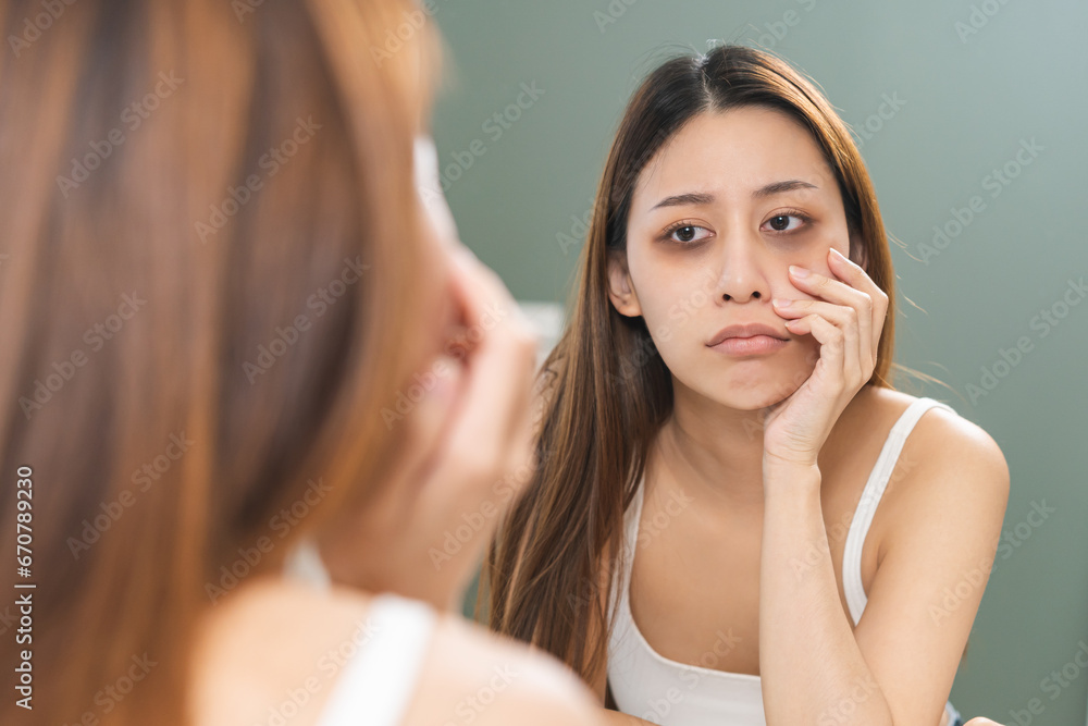 Bored, insomnia asian young woman, girl looking at mirror hand touching under eyes with problem of black circles or panda puffy, swollen and wrinkled on face. Sleepless, sleepy healthcare person. Bored, insomnia asian young woman, girl looking at mirror hand touching under eyes with problem of black circles or panda puffy, swollen and wrinkled on face. Sleepless, sleepy healthcare person.