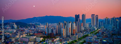 Moonrise over Daegu City skyline in South Korea, Apsan mountain and pink sky over the skyscrapers, office and residential buildings.  photo