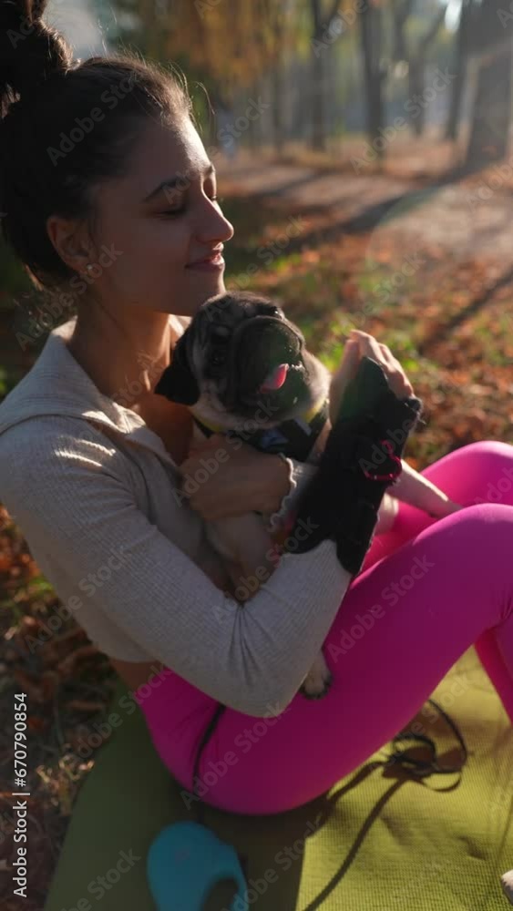 A sunny autumn morning is the perfect time for a young woman to walk with her pug dog. A sunny autumn morning is the perfect time for a young woman to walk with her pug dog.