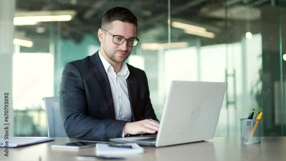Busy businessman in a formal suit typing on a laptop while sitting at a workplace in business office. Concentrated entrepreneur in glasses working on a project on the computer or chatting online Busy businessman in a formal suit typing on a laptop while sitting at a workplace in business office. Concentrated entrepreneur in glasses working on a project on the computer or chatting online
