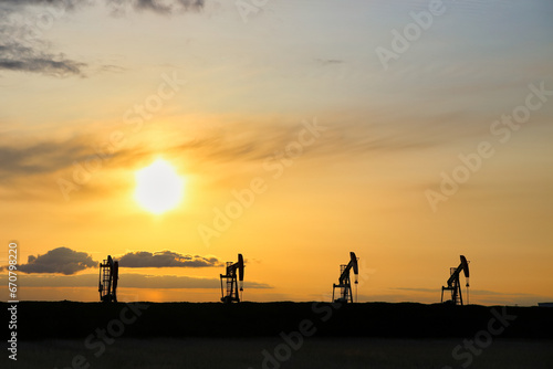 A row of oil pumpjacks at sunset
